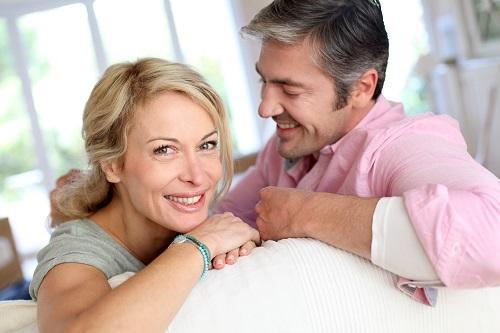 man smiling after woman while sitting on couch