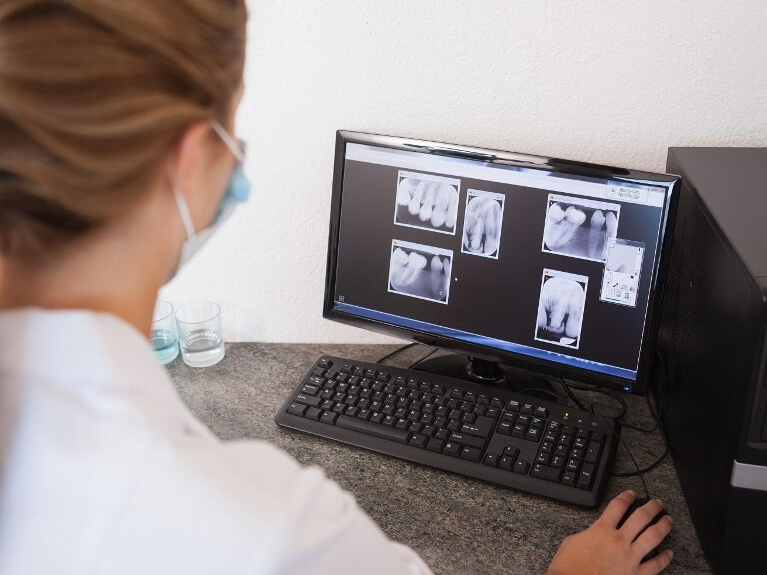Woman looking at dental xrays on computer screen