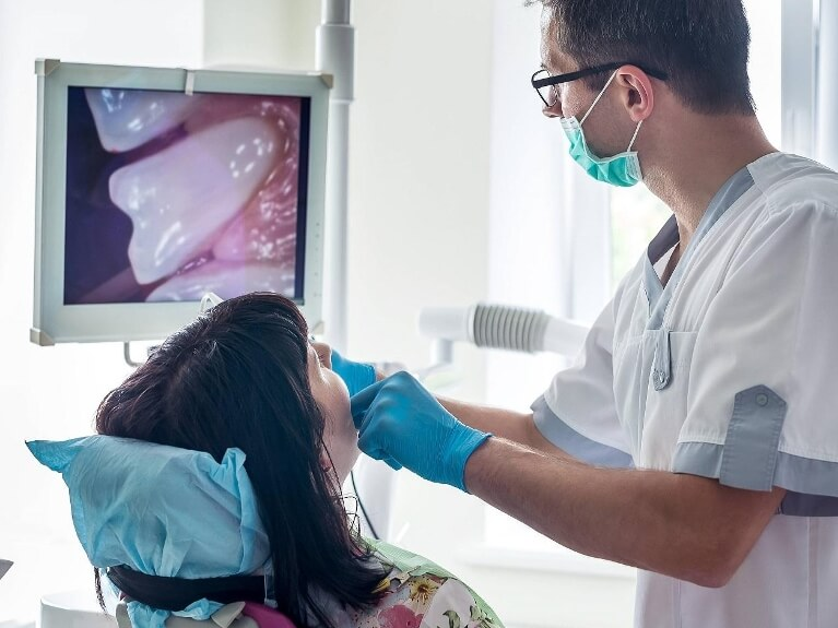 woman sitting in dental chair while dentist uses intraoral camera